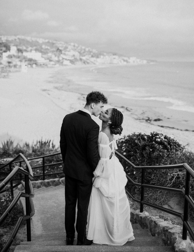 bride and groom kissing in front of laguna beach